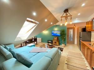 uma sala de estar com um sofá azul e uma cozinha em Kalinderu Ski Loft em Buşteni