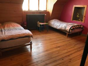 two beds in a room with a wooden floor at gite chez Régine in Marcenat