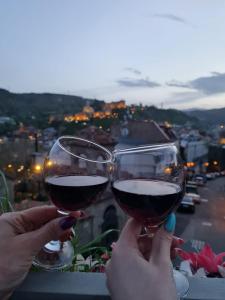 dwoje ludzi trzymających kieliszki wina na balkonie w obiekcie Hotel Vita w mieście Tbilisi City