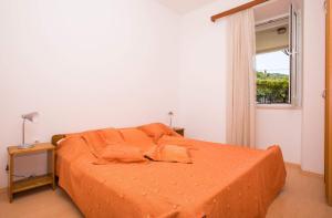 a bedroom with an orange bed and a window at Apartments Vidak in Molunat