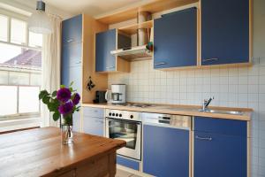 uma cozinha com armários azuis e um vaso de flores roxas em Sonneneck Rerik em Rerik