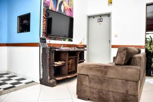 a living room with a chair and a television at Visk Palace Hotel e Restaurante in Foz do Iguaçu
