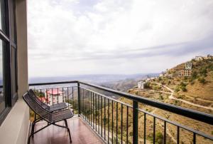 a balcony with a chair and a view at Kasauli Residency in Kasauli