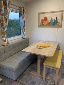 einen Tisch und eine Bank in einem Zimmer mit Fenster in der Unterkunft Nidd Way Holiday Let in Knaresborough