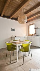 eine Küche mit einem Tisch und grünen Stühlen in der Unterkunft CaseOspitali - CASA CARAMELLI bilocale in corte storica in Cernusco sul Naviglio