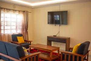 ein Wohnzimmer mit Stühlen und einem TV an der Wand in der Unterkunft Lodwar Acacia Residences in Lodwar