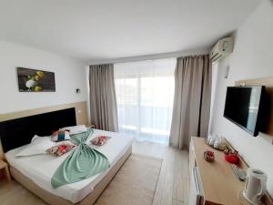 ein Hotelzimmer mit einem großen Bett und einem TV in der Unterkunft Vila Ryanna Beach pe plaja Belona in Eforie Nord