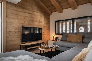 uma sala de estar com um sofá e uma televisão de ecrã plano em Spacieux duplex avec vue em La Clusaz