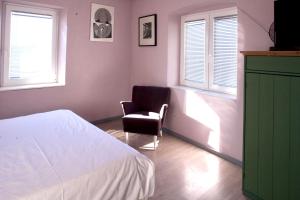 a bedroom with a bed and a chair and windows at Hana place in Motovun