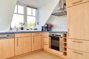 a kitchen with wooden cabinets and a stove top oven at Haffblick Rerik in Rerik