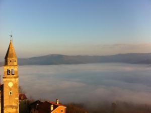 a building with a clock tower in the middle of a field of clouds at Hana place in Motovun