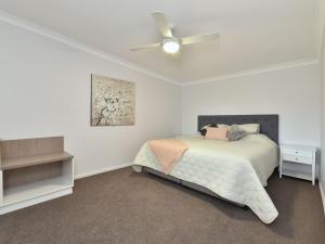 um quarto com uma cama e uma ventoinha de tecto em Malolo Park Guest House em Quorrobolong