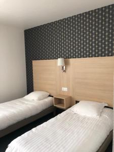 Habitación con 2 camas y pared con en Cit Hotel LA PYRAMIDE, en Romorantin-Lanthenay
