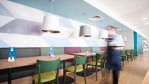 a man walks past a restaurant with tables and chairs at Holiday Inn Express Aberdeen Airport by IHG in Dyce