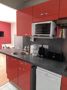 a kitchen with red cabinets and a sink and a microwave at Aux bons thermes in Argelès-Gazost