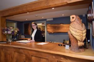 a woman sitting at a reception desk with a parrot statue at The White Hart Hotel in Moretonhampstead