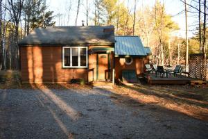 uma pequena casa com um alpendre e um deque em Brook Road Cabin em Goshen