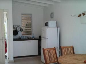 a kitchen with a white refrigerator and a table at Coco Beach Marie-Galante in Grand-Bourg