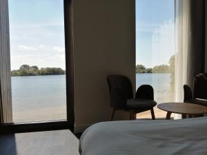 ein Schlafzimmer mit Blick auf einen See durch ein Fenster in der Unterkunft Domein Polderwind in Zuienkerke