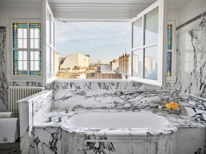 a white bathroom with a tub with a window at Le Meurice – Dorchester Collection in Paris