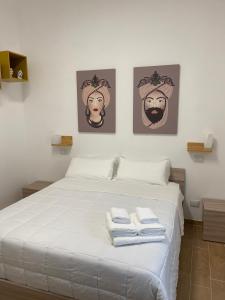 una camera da letto con un letto bianco e asciugamani di La Casa Dei Mori a Melilli