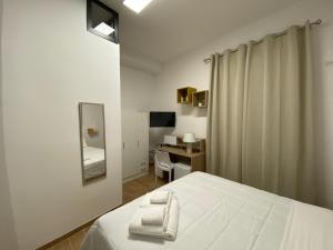 a white bedroom with a bed and a mirror at La Casa Dei Mori in Melilli