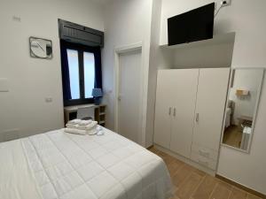a white bedroom with a bed and a flat screen tv at La Casa Dei Mori in Melilli +8 photos