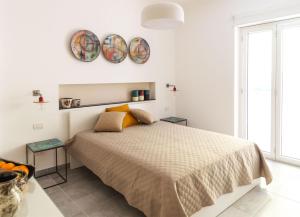 a white bedroom with a bed and two plates on the wall at Damè - Accommodation Amalfi Coast in Maiori