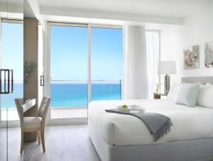 a white bedroom with a bed and a view of the ocean at Grand Beach Hotel Surfside in Miami Beach