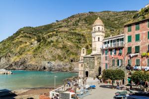 a town with a clock tower in front of a mountain at MADA Charm Apartments Piazza in Vernazza