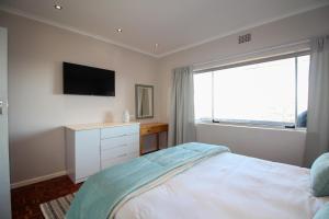 um quarto com uma cama, uma televisão e uma janela em Westward HO Apartment 13 em Cidade do Cabo