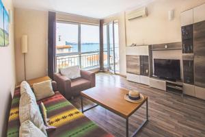 a living room with a couch and a table and a tv at Sea view Obzor Beach apartment in Obzor