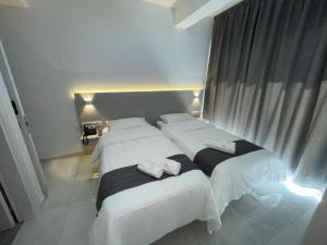 two beds in a hotel room with white sheets at La Veranda Hotel in Larnaca