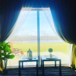 two tables in front of a window with a view at Kempings Kalnavoti in Koknese