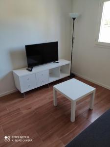 a living room with a tv on a white cabinet at Charmant studio avec piscine et clim (en été) in Aix-en-Provence