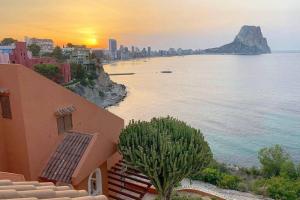 a view of a beach with a building and the sunset at Panoramic sea and Ifach views in Calpe in Calpe