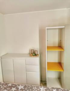 a small kitchen with white cabinets and a shelf at Mobile Home Rock 'n' Sea in Sveti Juraj