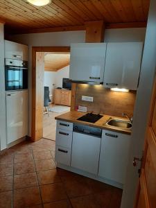 una cocina con armarios blancos y fregadero en Alpenhof Strenge, en Birnbaum
