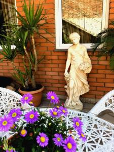 une statue d'une femme assise sur une terrasse couverte à côté des fleurs dans l'établissement GREEN GARDEN, à Tbilissi