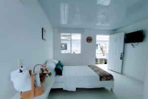 a white bedroom with a bed and a television at Hotel Boutique los Remansos in Palmira