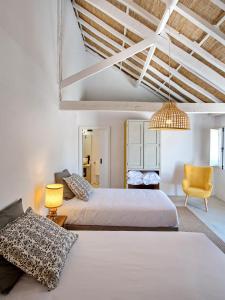 a bedroom with two beds and a yellow chair at Castelo de Arez in Alcácer do Sal