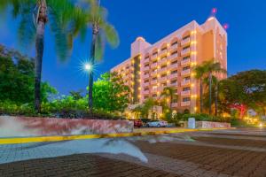 a hotel at night with palm trees and a street at Hotel Lucerna Culiacan in Culiacán