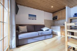 a living room with a couch and a kitchen at Résidence Aiguille Lodge in Les Deux Alpes