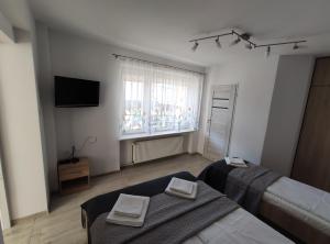 a bedroom with two beds and a television and a window at Willa Rodzinna in Władysławowo