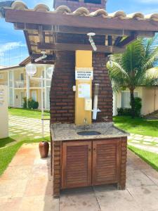 une cuisine extérieure avec un évier sous une pergola dans l'établissement FLAT em residencial! Praia de taperapuan!, à Porto Seguro