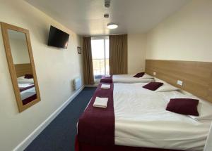 una camera d'albergo con due letti e uno specchio di PremierLux Serviced Apartments a Ilford