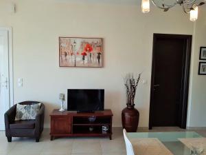 a living room with a tv and a chair and a table at Bel Air in Skala Potamias