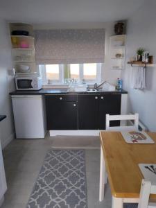 eine kleine Küche mit einem Waschbecken und einem Tisch in der Unterkunft Brick Kiln Apartment in Campsey Ash