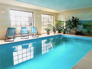 una piscina con 2 sillas azules y plantas en Ein Bett im Kornfeld - Haus Fernweh - Innenpool, en Schönfeld