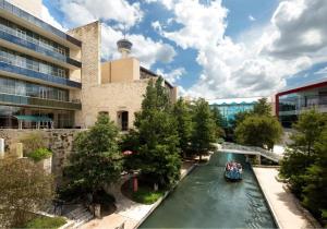 a boat on a river in front of a building at Grand Hyatt San Antonio River Walk in San Antonio